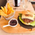 Hamburguesa de ternera IGP Carne de Ávila con queso de cabra gratinado, lechuga y cebolla caramelizada, acompañada de patatas fritas, en el restaurante La Posada del Agua