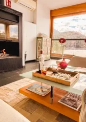 Salón con chimenea y ventanal con vistas a la sierra de Gredos, ambiente acogedor para descansar en La Posada del Agua