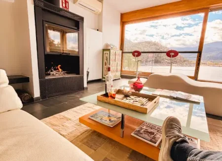 Salón con chimenea y ventanal con vistas a la sierra de Gredos, ambiente acogedor para descansar en La Posada del Agua